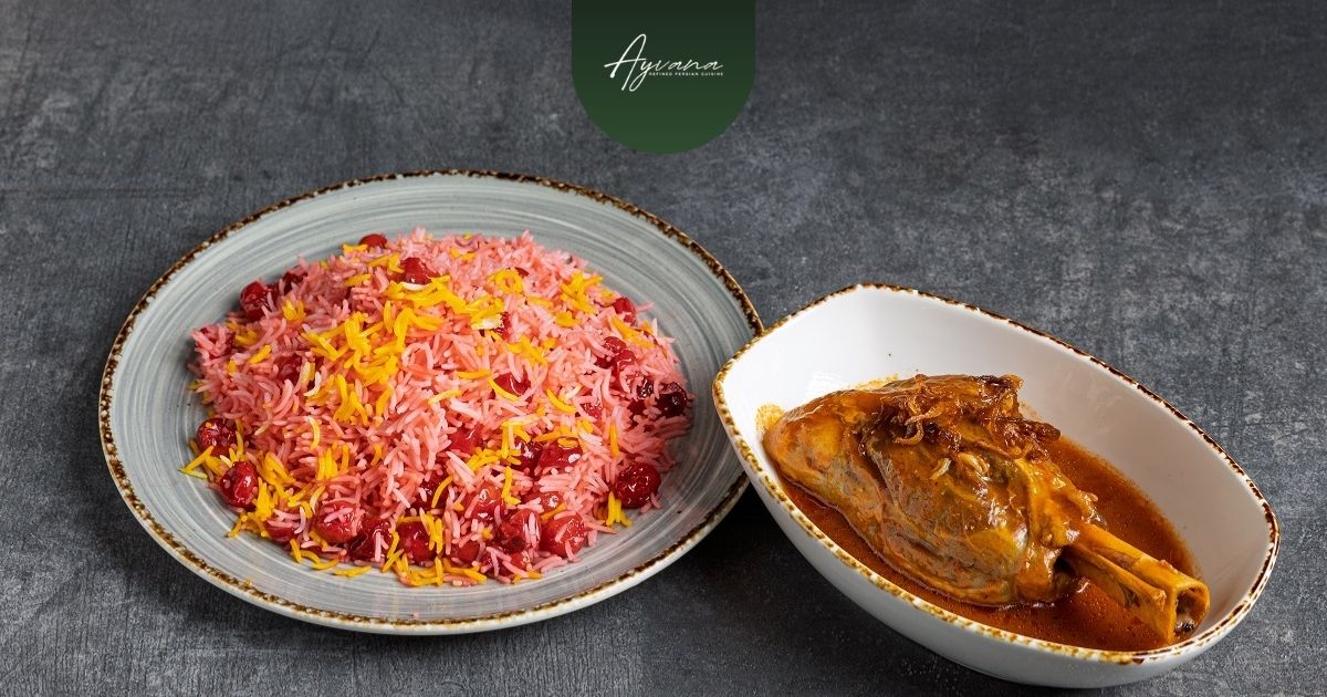 Albaloo Polo (Sour Cherry Rice) rice served alongside braised lamb shank in rich sauce on a restaurant table.