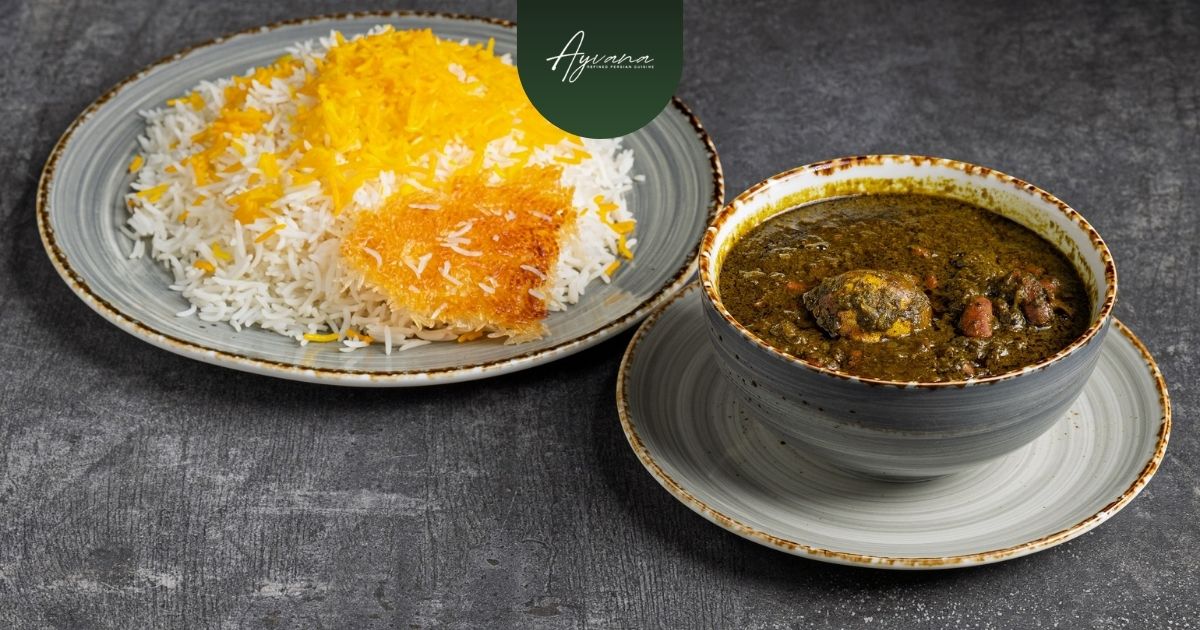 Bowl of rich green Ghormeh Sabzi Persian herb stew with meat and beans, served alongside saffron rice with golden tahdig at Ayvana.